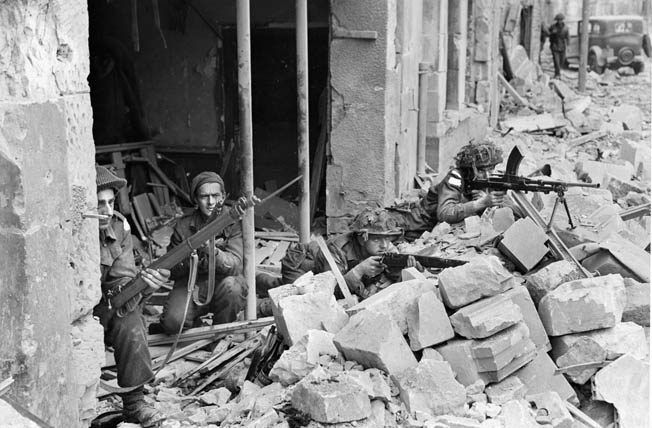 Fighting was intense in the towns and villages behind Juno Beach. Here, 3rd Canadian Infantry Division soldiers defend their position in a French town. Three of the soldiers are equipped with Lee Enfield Mk I rifles while the soldier at right is firing a Bren .303 Mk II machine gun. 