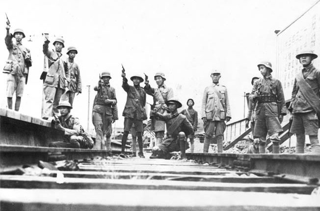 Chinese troops strike heroic poses for a photographer during the Second Sino-Japanese War. Note that some of these Chinese soldiers are wearing the German coal scuttle-style helmet. German military advisers trained numerous units of the Nationalist Chinese Army.