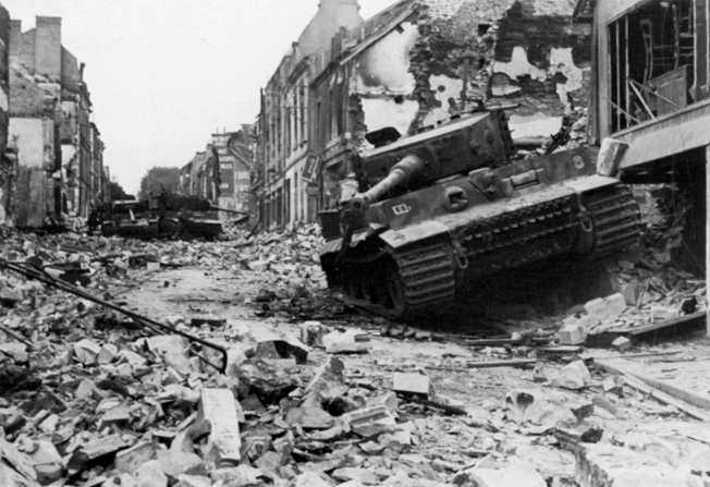 On June 30, 1944, two weeks after Wittmann’s astounding feat of gunnery, his Tiger I tank lies dis- abled and abandoned in Villers-Bocage following an Allied bombing attack. 