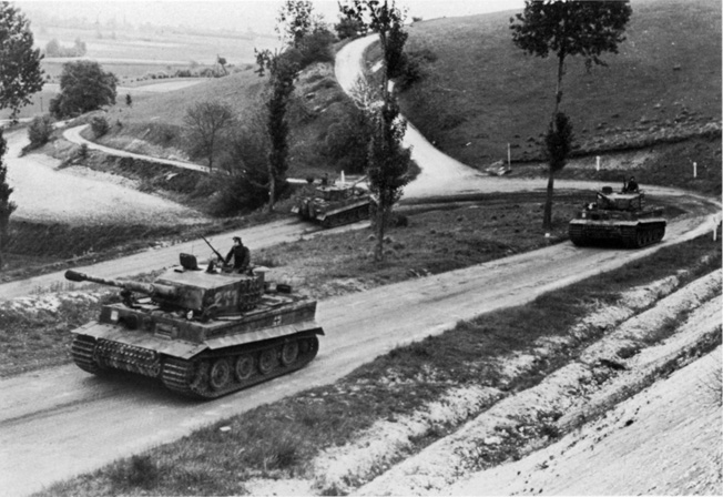 The Tigers of Obersturmführer Michael Wittmann’s 2nd Company of the 101st SS Heavy Tank Battalion round a curve on their way to the front. 