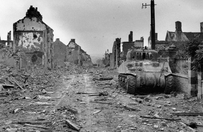 The British recaptured what was left of Villers- Bocage on August 5, 1944. This view of a knocked- out Sherman tank and ruined buildings reveals the extent of the damage that two months of fierce combat had wrought.