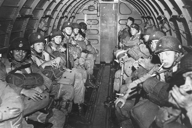 Laden with combat gear, American airborne troops await orders to stand up, hook up, and jump.