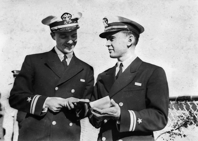 Young Ensign Gene Verge, right, confers with a fellow officer. During the harrowing attack on Pearl Harbor, Verge took command of the seaplane tender USS Curtiss.
