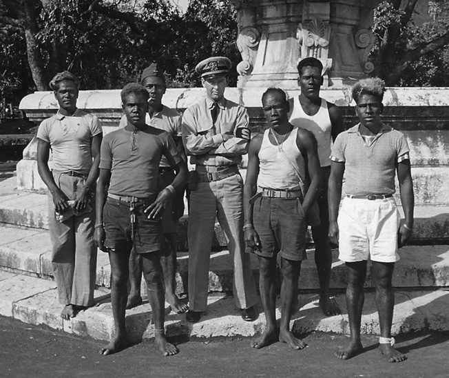 Gene Verge photographed with South Pacific islanders employed by the Navy, loading and unloading ships.