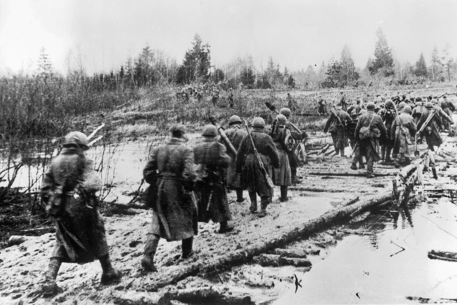 Soviet troops cross a stream on an improvised bridge to take the fight to the enemy still trapped in the Demyansk Salient, summer 1942.