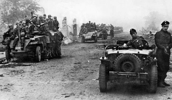 A German soldier drives a captured American jeep while several Sd.Kfz. 250/1 light armored cars (left) are piled with infantry on the Western Front in Holland. Initially caught off guard, the Germans fought back fiercely.