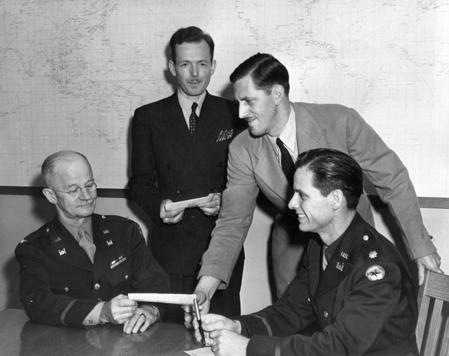 Major John S. Detlie, far right, poses with Colonel Richard Park, Seattle District Engineer, and two civilians who received checks as part of an “Ideas for Victory” promotional campaign. Detlie, an art director and set designer for MGM Studios, was in charge of camouflaging Boeing’s Seattle aircraft plant. 