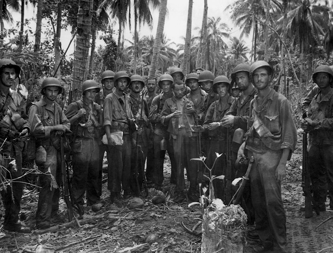 A lone Japanese prisoner, captured during a scouting mission, is photographed with his Marine captors. 