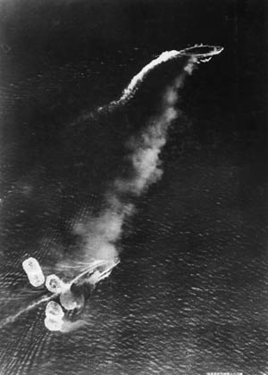 Japanese aerial photo taken during high-level bombing attack against the battleship HMS Prince of Wales (upper right) and HMS Repulse (lower left), December 10, 1941. Repulse has just been hit by one bomb and near-missed by several more. Both ships were sunk.