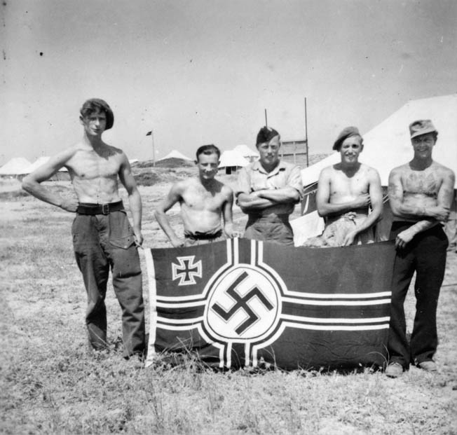 After returning from one of their trademark covert operations, these SBS men pose proudly with the ensign of the Kriegsmarine, the German Navy. 