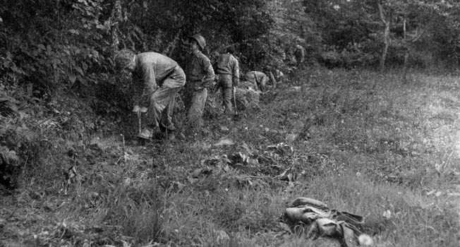American soldiers dig in along the edge of a hedgerow. The Americans learned quickly to dig in and hug the hedgerows when enemy shelling began.