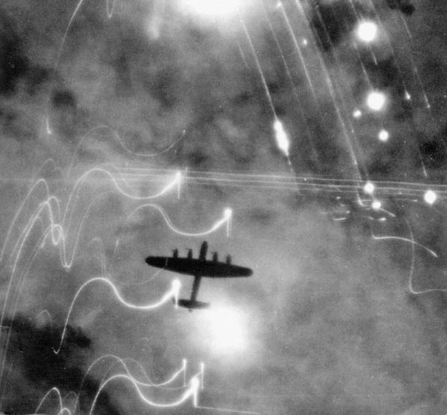 Looking down on a British Lancaster bomber over Hamburg. Fires on the ground and the white streaks of anti-aircraft munitions are clearly visible.