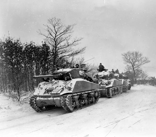 Four Sherman tanks with 76mm guns form a line along a snowy Luxembourg road. The 707th Tank Battalion helped bolster Flynn’s defense of Hosingen—for a while.