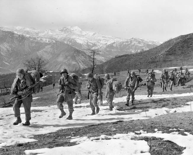 A line of 10th Mountain Division soldiers climbs Mount Belvedere, north of Florence, Italy, February 20, 1945. The hotly contested Riva Ridge is visible in the background.