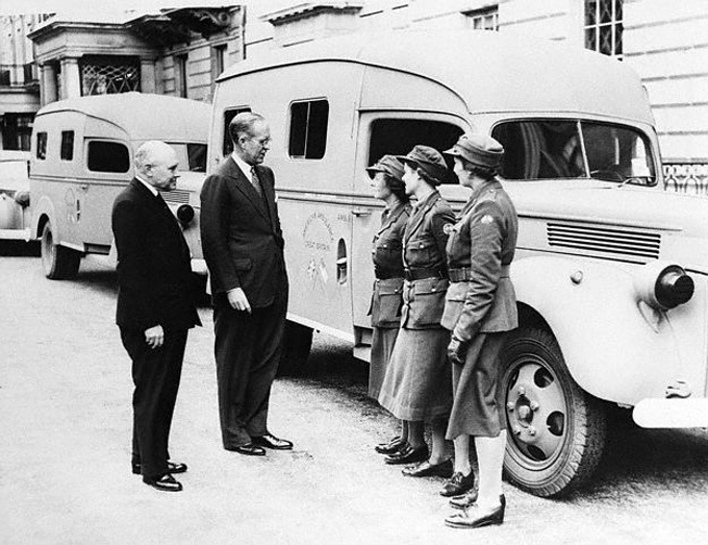 Kennedy, center, talks with volunteer drivers of the “American Ambulance Unit of Great Britain” in London, July 1940. Kennedy donated the money to purchase one of the vehicles. 