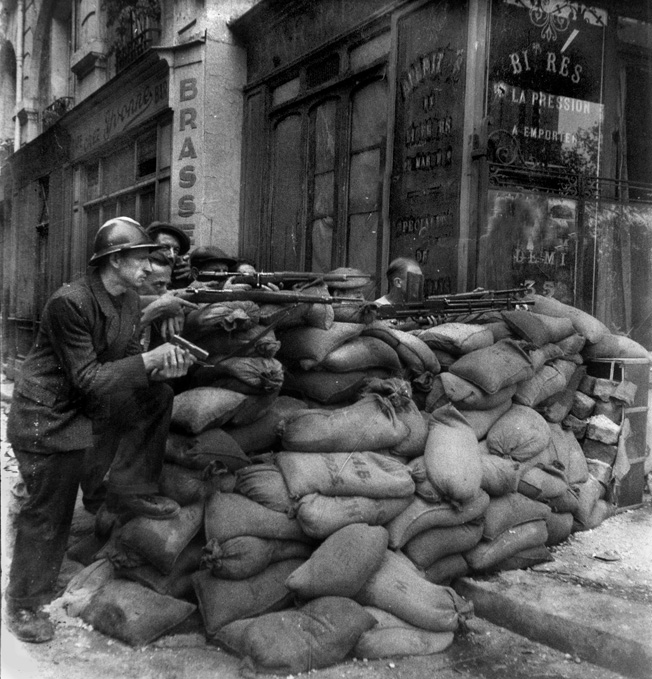 Free French Army soldiers behind a barricade in the streets of Paris, France during the Liberation of Paris. Photograph, August 1944.