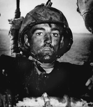 As he climbs aboard a transport off the island of Eniwetok, a U.S. Marine wears the expression of a fighting man who has endured continued hardship.