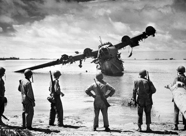 After Makin has been secured, American soldiers inspect the wreckage of a Japanese Kawanishi H8K flying boat that lies in the surf. The aircraft was damaged during the preinvasion bombardment and then used by the Japanese defenders as a machine-gun position. 