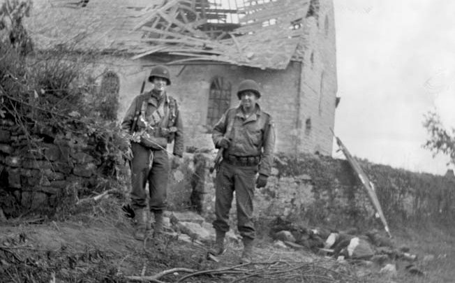 Shortly after the fighting at La Fière concluded, these American soldiers paused for a photographer with the heavily damaged manor house in the background. The bitter fighting at La Fière was a harbinger of combat to come in Normandy. 