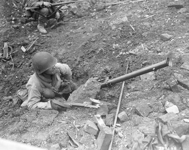 During the fighting at La Fière, American paratroopers of the 82nd Airborne Division handled bazookas with great skill and held German armor at bay. This paratrooper takes cover beside a roadway near La Fière, his bazooka nearby.