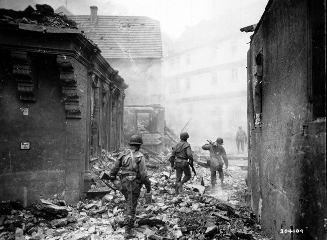 GIs from a machine-gun squad move through the rubble of a destroyed German town in early April 1945. 