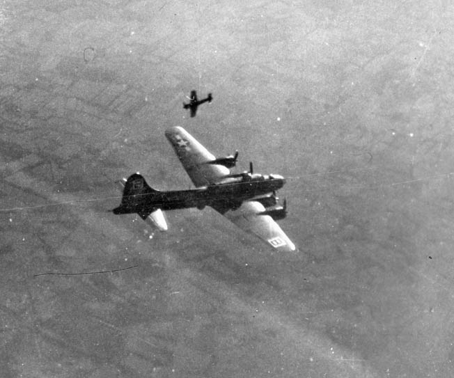 A B-17 of the U.S. Eighth Air Force flies high above the German city of Bremen during a bombing raid in November 1943. Also captured in this image is a fighter plane, possibly an American P-47 Thunderbolt, streaking in the opposite direction while flying escort.