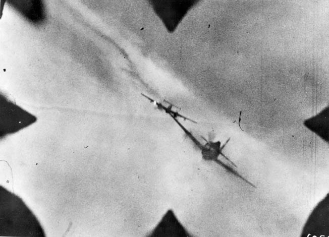 This still photograph from the gun camera of a Republic P-47 Thunderbolt fighter depicts an attack on a German twin-engine Messerschmitt Me-110 fighter. The German pilot has apparently attempted to position himself to attack the big, four-engine B-17 bomber in the distance; however, the hunter has become the hunted.