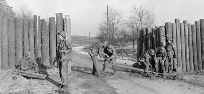 On January 2, 1945, the day after the German Army launched Operation Nordwind, engineers of the 106th Cavalry Squadron prepare a roadblock to slow the enemy advance a half mile from the town of Ludweiler, Germany.