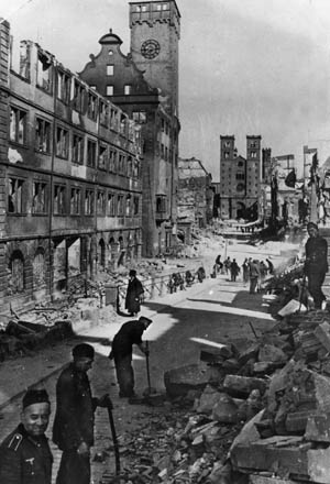 German soldiers and civilians clear rubble from Domstrasse in Würzburg, March 1945. In the distance is St. Kilian’s Church, circa 1050.