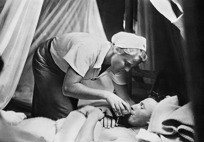 A nurse provides a drink to a wounded soldier in a Luftwaffe hospital in North Africa, 1942.