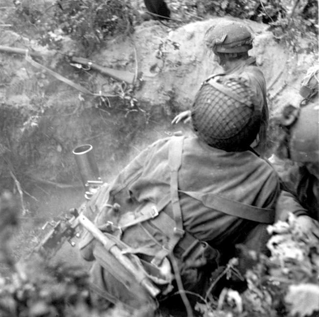 British fighters use a three-inch mortar to fend off Germans.