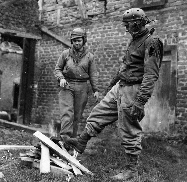 Two tankers with the 2nd Armored Division warm their feet by a fire in Beggendorf, Germany. They had just finished fighting for more than 24 hours without a rest.