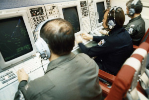 Air Force surveillance and U.S. Customs officers monitor multipurpose consoles aboard an E-3A, December 1978.