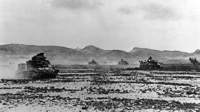 American M-3 Lee tanks, with hull-mounted 75mm cannons and 37mm turret-mounted guns, raise clouds of dust in the Tunisian desert.