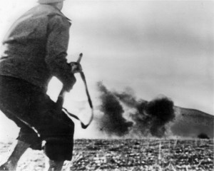 Blast from a German bomb rattles this GI as he moves into position at Kasserine Pass.