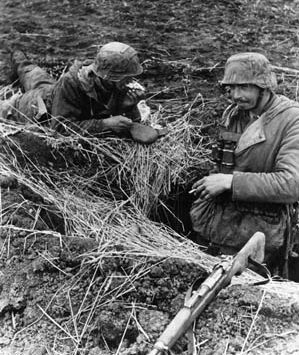 During the lull in the fighting on the steppes of Russia, a pair of German soldiers smoke a cigarette and eat a quick meal at their somewhat exposed position.