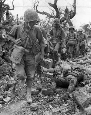 A line of Marines passes the body of a dead Japanese soldier, May 24, 1945. The tenacious defenders preferred death over dishonor. 