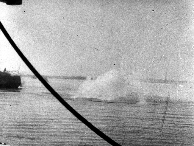 A near-miss from a Japanese bomb detonates in the water near the stranded oil tanker Miping, which was also sunk by the marauding Japanese.