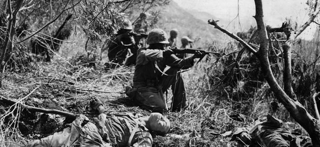 Amid the bodies of dead Japanese soldiers, a Marine of the U.S. 2nd Division raises his M1 carbine to take aim at the retiring enemy on Saipan during the advance on Mount Marpi. The bitter battle for Saipan resulted in heavy casualties for both sides.