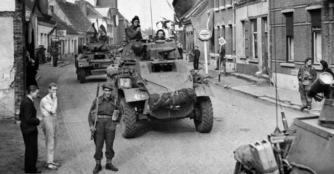Daimler and Humber armored cars pass through the Belgian-Dutch border town of Putte during the Anglo-Canadian drive to cut off the German Fifteenth Army on the islands of the Scheldt Estuary, October 11, 1944.