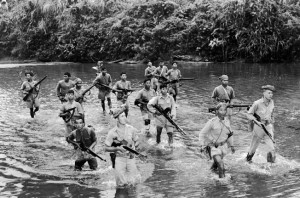 American-led Burmese guerrillas cross a shallow river in central Burma, ever alert for enemy snipers.