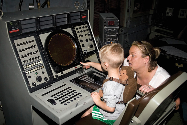 A mother and son at a cockpit flight simulator. 