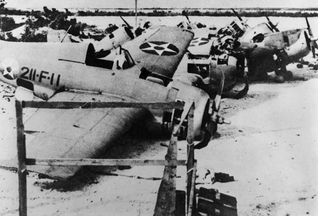 In the aftermath of Wake Island, wrecked American Wildcat fighter planes from Marine squadron VMF-211 litter the runway. 