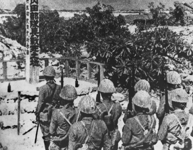 Japanese troops stand at attention to honor their fellow soldiers who were killed in the stubborn American defense of Wake Island.