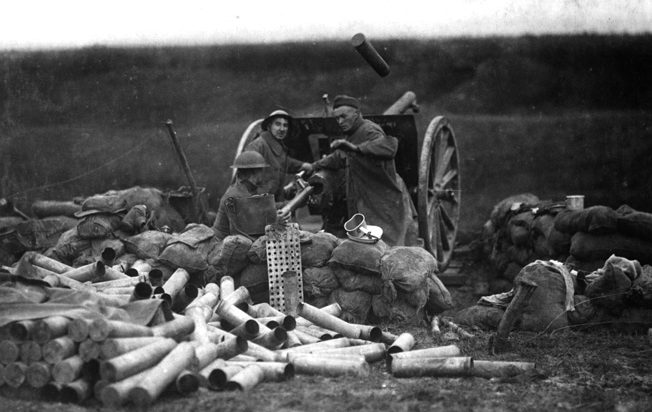 An American gun crew fires the French 75 gun at Saint-Michel, France, in September 1918. Note the large pile of expended shells and ammunition packing tubes behind the gun, indicating its high rate of fire. A shell casing is still in the air above the cannon.