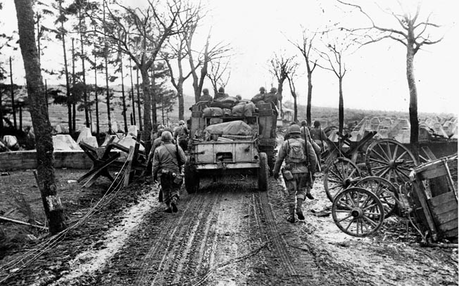 Men and vehicles make their way through a breach in the Siegfried Line’s Dragon’s Teeth. Miller watched as a tank dozer shoved dirt over the Dragon’s Teeth, allowing the men to cross unimpeded. 