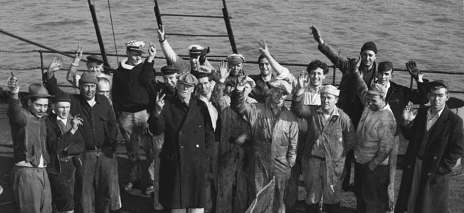 Happy to have survived an attack by the German submarine U-123 off Cape May, New Jersey, crewmen of the tanker SS Malay give the “V for Victory” gesture as they gather around damage inflicted on their ship. 