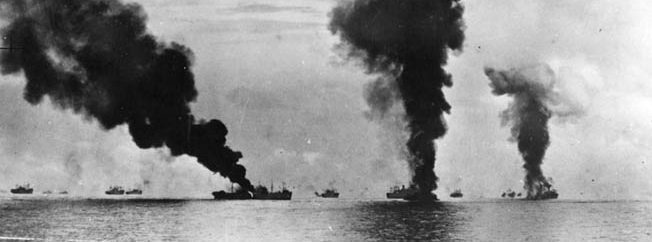 This photo was taken shortly after the one above and depicts the burning transport George F. Elliott, hit by a Japanese plane, at left center. The other columns of smoke are from Japanese aircraft that have been shot down and crashed into the sea. 