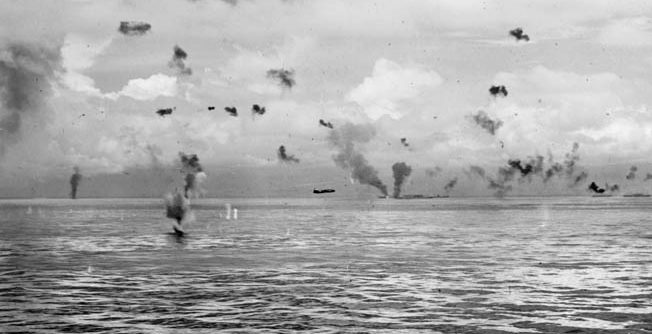 A Japanese Mitsubishi G4M Betty bomber makes a torpedo run against American ships of the Tulagi invasion force. This photo was taken on August 8, 1942. The blazing ship in the distance is probably the transport George F. Elliott.