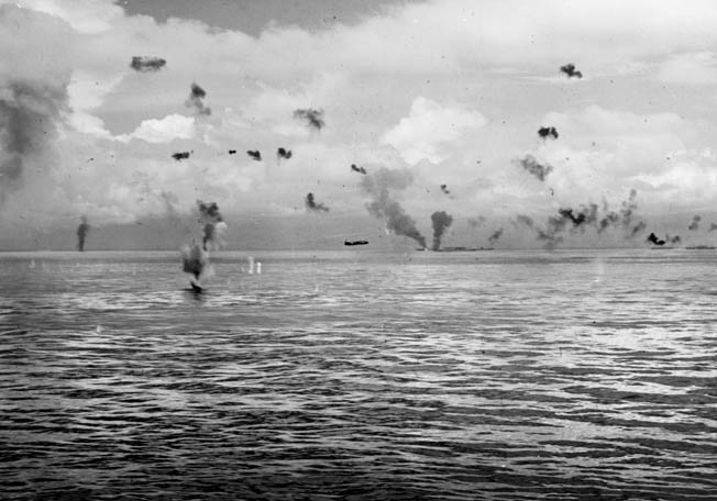 A Japanese Mitsubishi G4M Betty bomber makes a torpedo run against American ships of the Tulagi invasion force. This photo was taken on August 8, 1942. The blazing ship in the distance is probably the transport George F. Elliott.